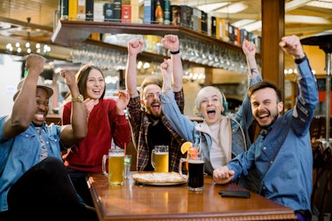 Excited diverse friends football fans celebrating victory goal score watching game online on tv in c...