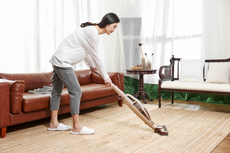 Young asian woman use wireless vacuum cleaner to clean