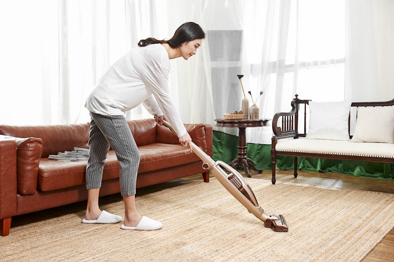 Young asian woman use wireless vacuum cleaner to clean