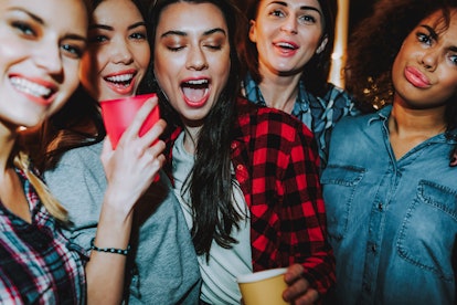 A group of women smile and pose for a picture at a party.