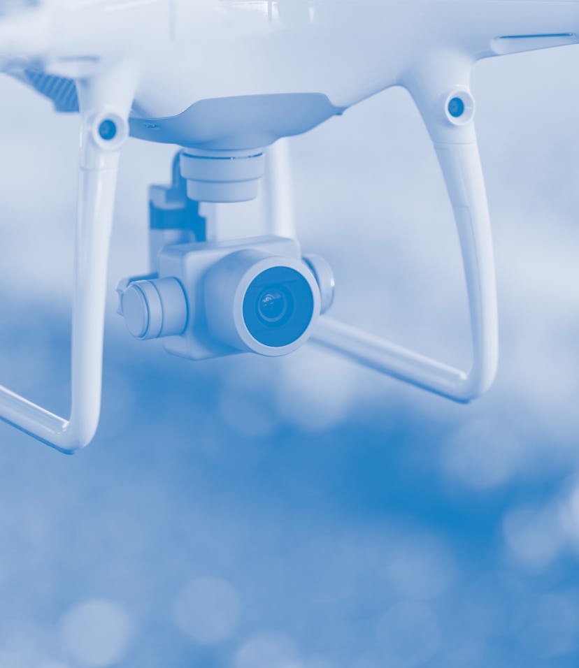 Close up on white drone camera. Drone quadcopter in flight