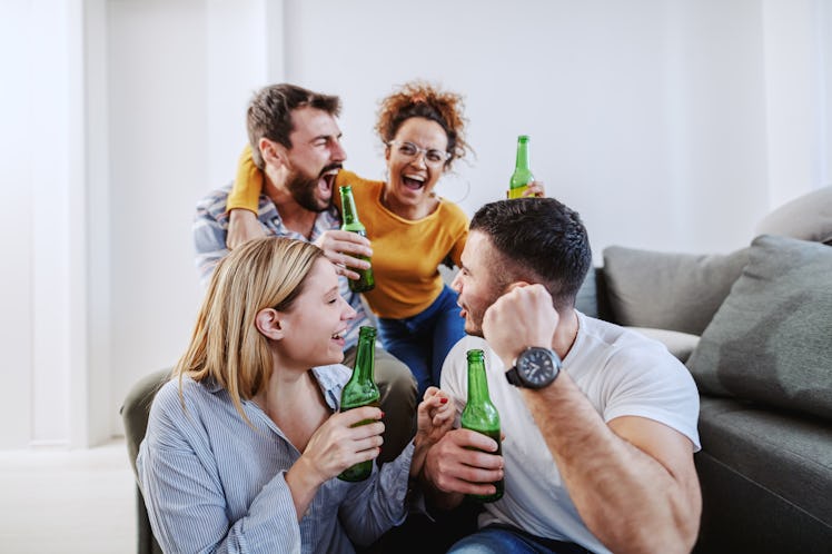 A group of friends enjoys beer and laughs in a bright family room.