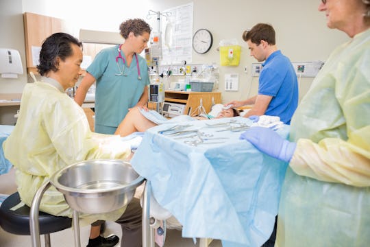 a hospital delivery room with a doctor caring for mom in bed, nurses, and father