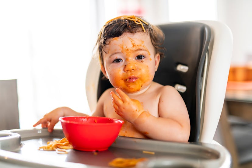 child girl, eating spaghetti for lunch and making a mess at home in kitchen