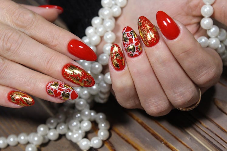 fashionable red manicure with a gold heart design