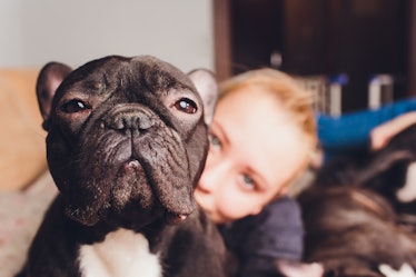 A blonde woman cuddles with her French bulldog.