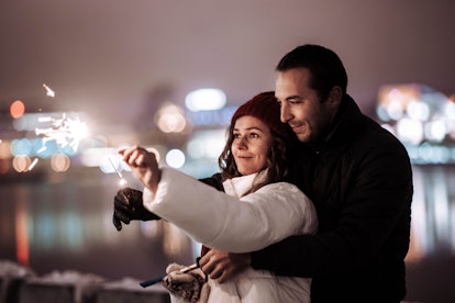 couple in love on a winter date in the city with sparklers in the evening on Christmas holidays.