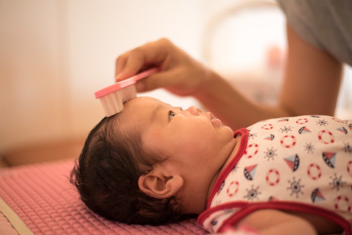a baby girl getting her hair brushed