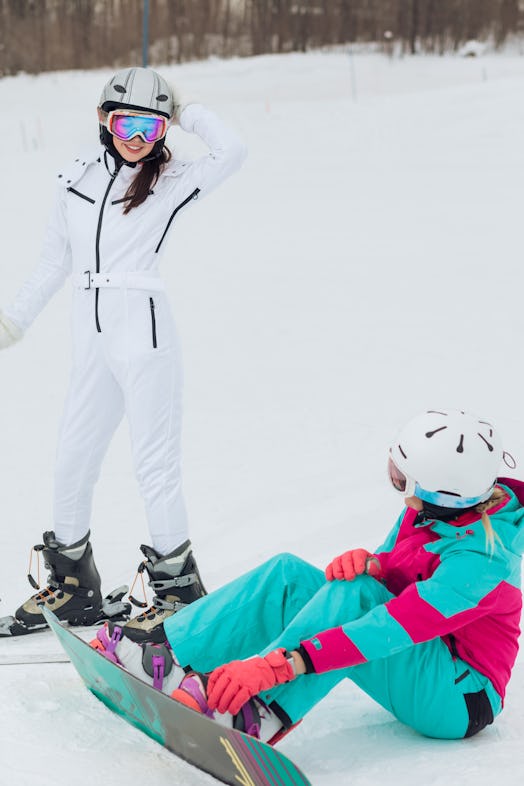 An athletic couple shares a moment while skiing and snowboarding on a snowy mountain.