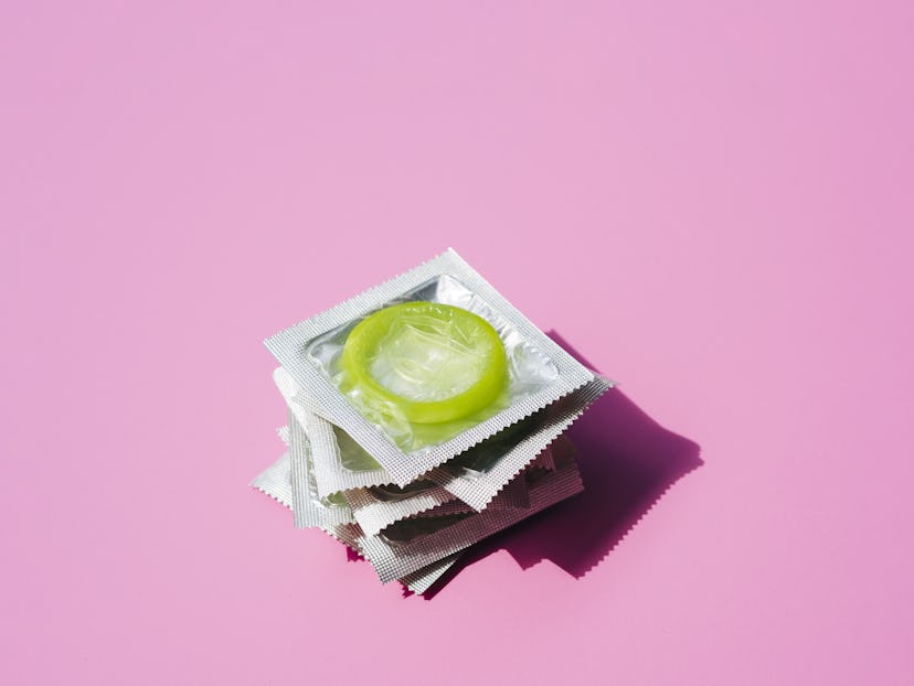 High angle pile of condoms on pink background. Some people choose to use condoms in a long term rela...