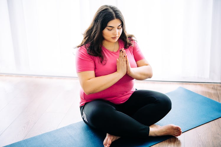 Beautiful plus size girl meditating indoors. Yoga and wellness concept