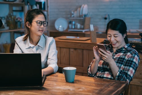 Angry business worker woman looking at lazy mate playing with the smart phone. annoyed young girl ro...