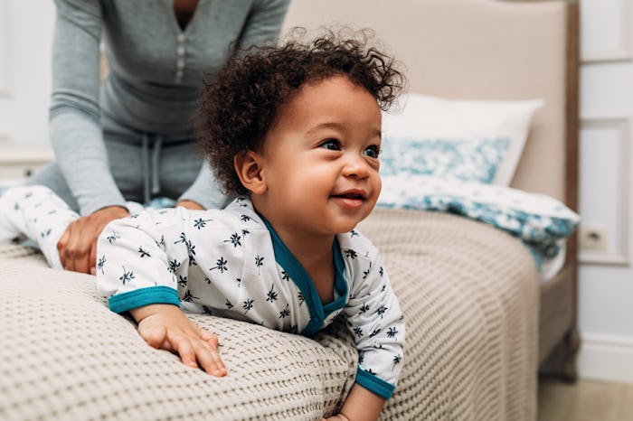 Mother playing with son on a bed. Close up of baby boy looking away.