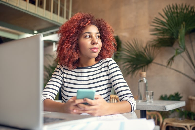 Woman holding phone. Young red-haired woman holding phone while texting her boyfriend