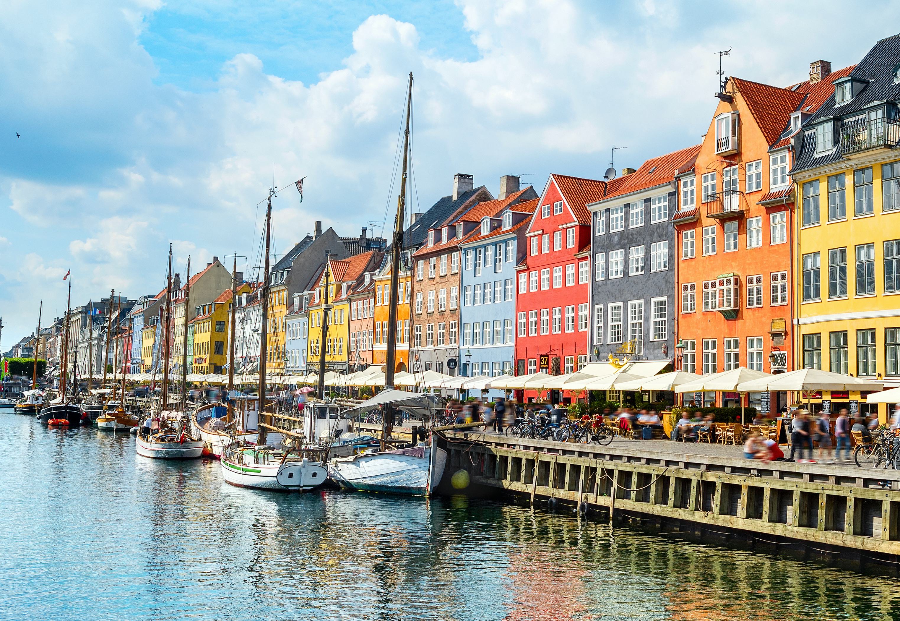 People  at sunny Nyhavn embankment with moored yachts, Copenhagen, Denmark