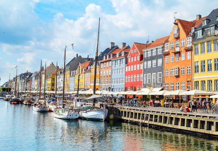 People at sunny Nyhavn embankment with moored yachts, Copenhagen, Denmark
