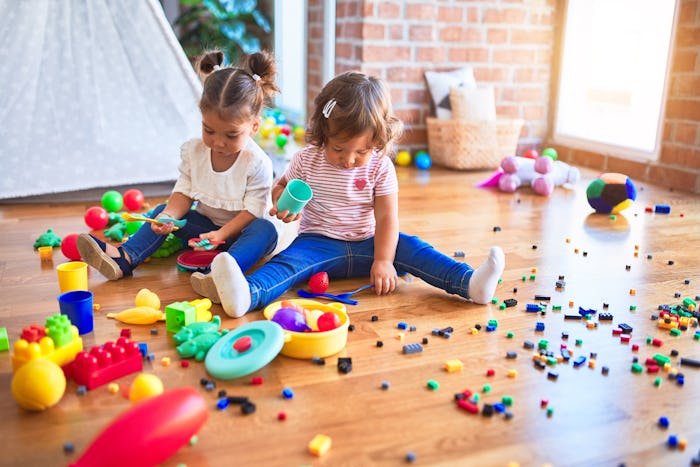 toddler girls playing with toys on the floor 
