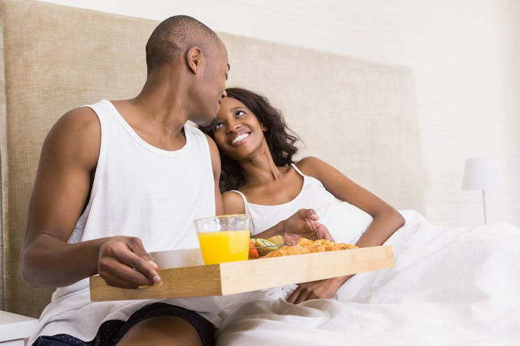 Young man serving breakfast to woman in the bed