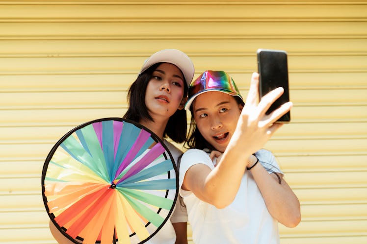 Selfie of lesbian couple infront of yellow rolling steel door with a colorful wheel.