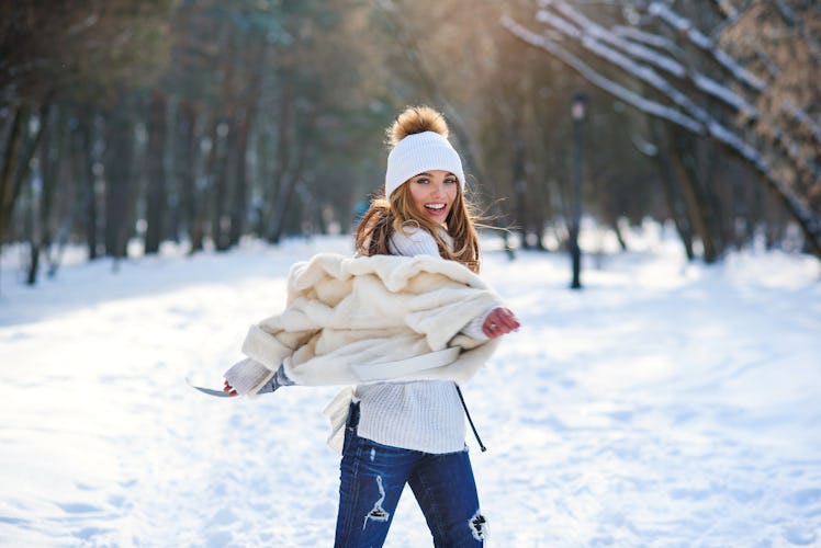 Beautiful young woman having fun and dancing in winter snowy park.