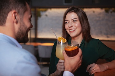 Beautiful cheerful woman enjoying night out with her boyfriend at cocktail bar. Couple celebrating a...
