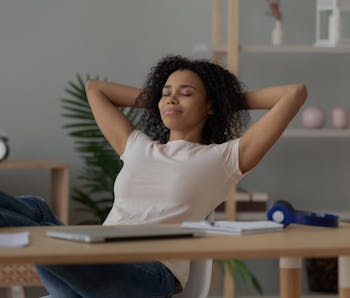Happy calm african girl student relaxing holding hands behind finished study work breathing fresh ai...