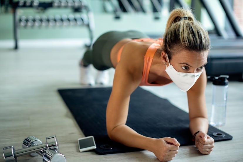 woman wearing a face mask doing planks at the gym
