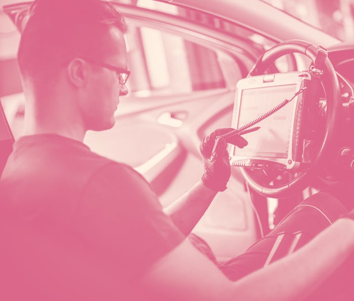 Automobile computer diagnosis. Car mechanic repairer looks for engine failure on diagnostics equipme...