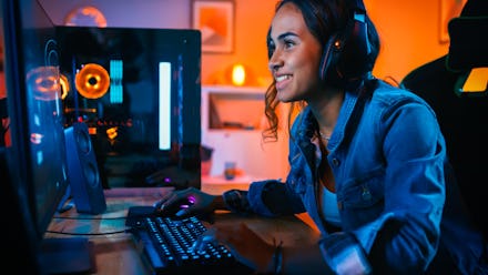 Pretty and Excited Black Gamer Girl in Headphones is Playing First-Person Shooter Online Video Game ...