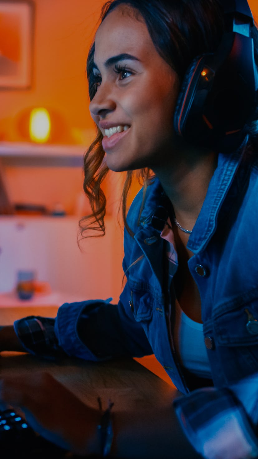 Pretty and Excited Black Gamer Girl in Headphones is Playing First-Person Shooter Online Video Game ...