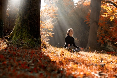A young woman make yoga position at sunrise. in the autumn forest