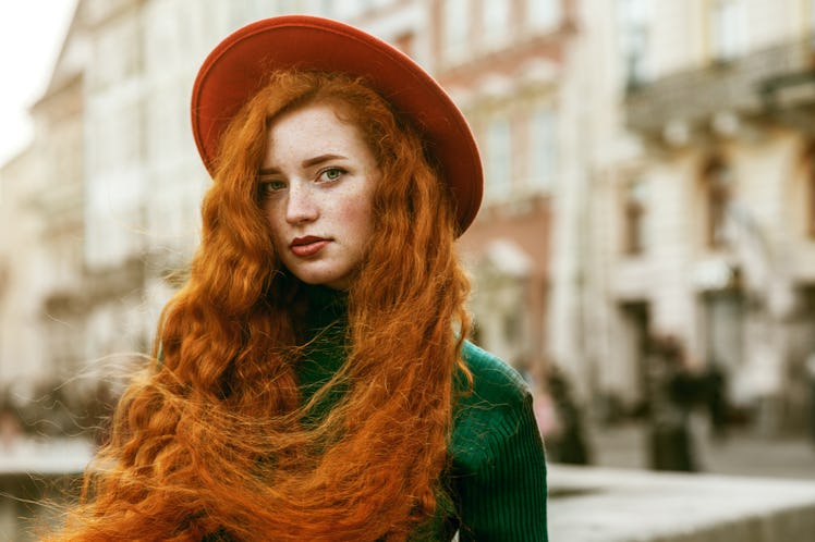 Close up portrait of young beautiful fashionable redhead woman with freckles, very long curly hair, ...