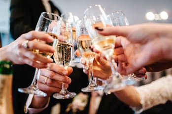 Cheers! People celebrate and raise glasses of wine for toast. Group of man and woman cheering with c...