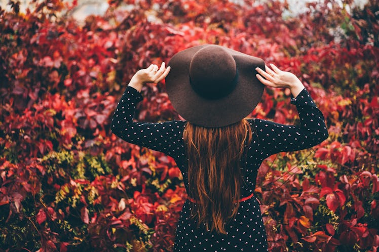 Young woman surrounded by autumn leaves, thinking about how her unlucky zodiac sign will have the wo...