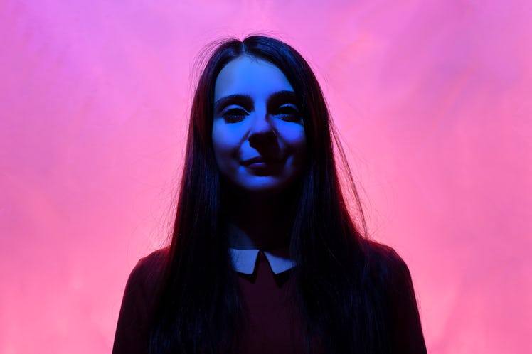 Portrait of young brunette girl with dark eyes in red and blue neon. Woman in red dress with white c...