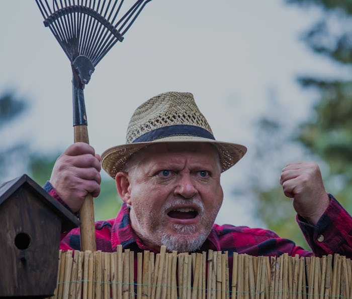 An evil, aggressive man watches his neighborhood over the garden fence. Concept dispute and aggressi...