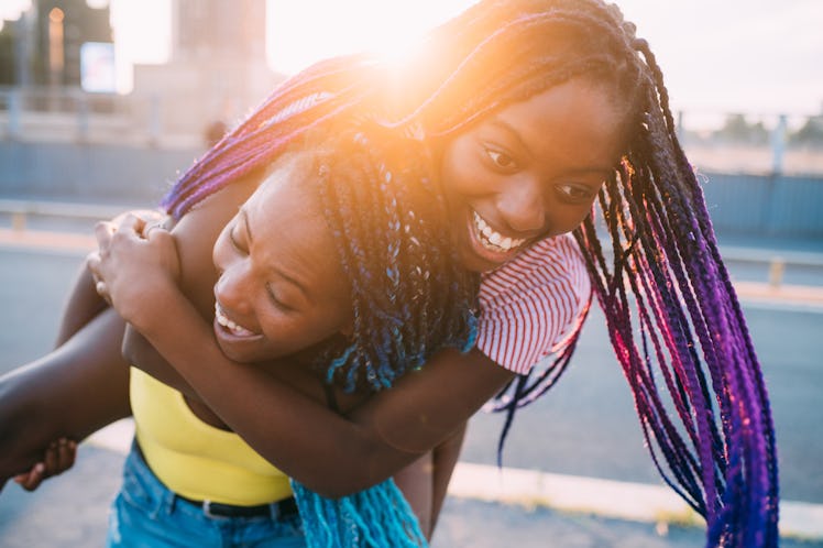 Close up two sisters outdoor back light outdoor hugging having fun - happiness, fooling around, toge...