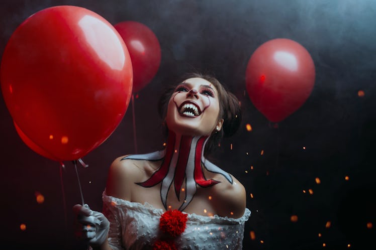 close-up portrait female clown woman scary crazy smiling laugh shows sharp teeth predator face, hold...
