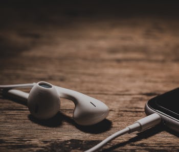 earphones and phone media portable on dark tone. selective focus of earphones.