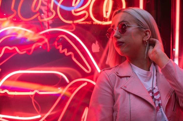 Cinematic portrait of blond girl with pink leather jacket on neon sign at night