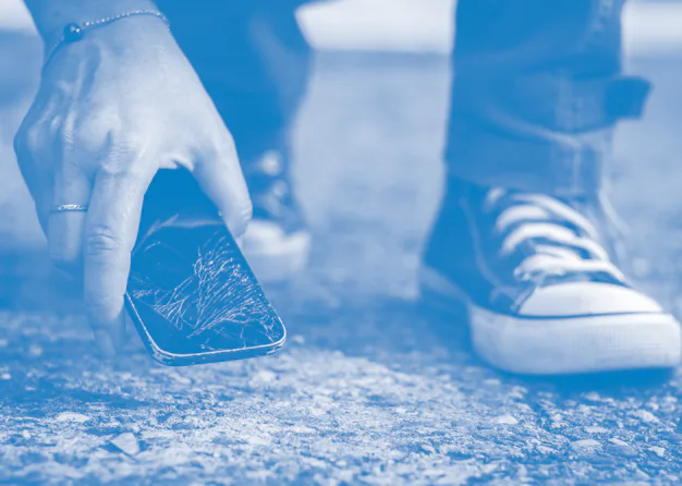 Woman picking up broken smartphone from the ground. Damaged mobile phone with cracked touch screen.