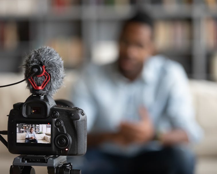 Close up focus of modern professional camera shooting african American male coach or tutor making vl...