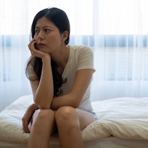 Bad mood in morning at home. Young depressed asian woman sitting on bed consider about problems. ups...
