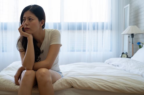 Bad mood in morning at home. Young depressed asian woman sitting on bed consider about problems. ups...