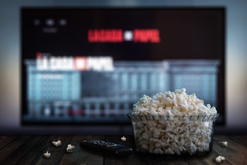 Video streaming app on tv screen behind a bowl of popcorn and a remote control.