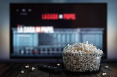 Video streaming app on tv screen behind a bowl of popcorn and a remote control.