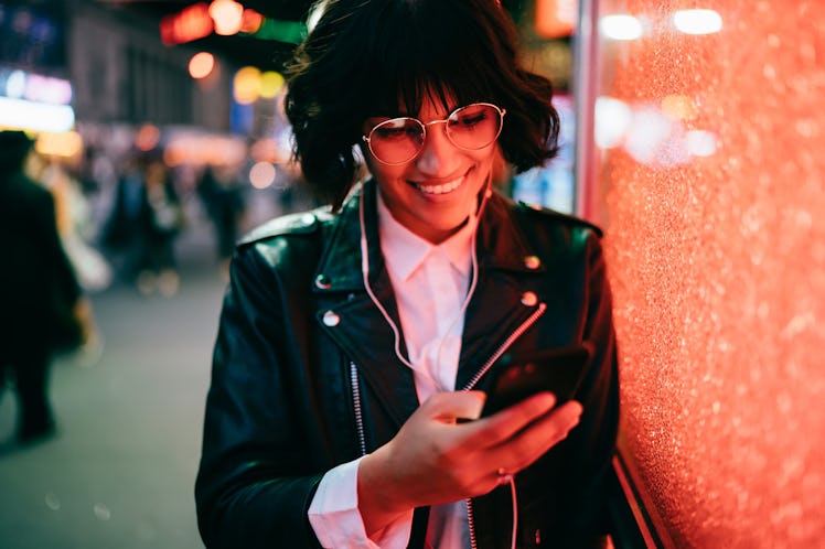 Happy hipster girl in optical spectacles checking shared video web content listening sounds in elect...