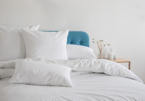 White pillows, duvet and duvet case on a blue bed. White bed linen on a blue sofa. Bedroom with bed ...