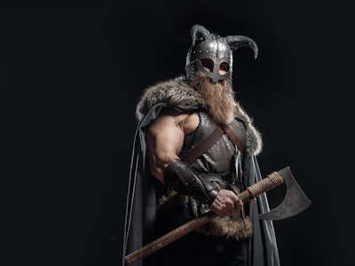 Warrior Viking in full arms with axe and shield on dark background