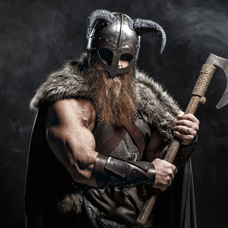 Medieval warrior berserk Viking with axes attacks enemy. Concept historical photo of Scandinavian go...
